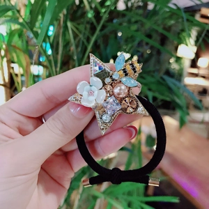 Detail view of handmade star hair tie with colorful rhinestones and pearls on a black elastic