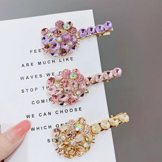 Close-up of three sparkling rhinestone kitten hair clips in purple, pink and champagne