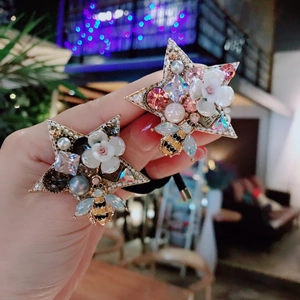 Detailed shot of star-shaped hair ties with rhinestones, pearls, and a small bee charm