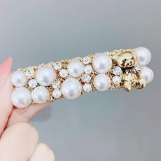 Detail of elegant gold hair clip with pearls, rhinestones, and a small bear charm