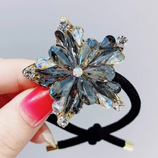 Close-up of star-shaped crystal hair tie with blue teardrop stones and black elastic band