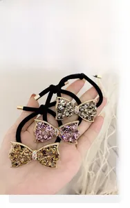 Detailed shot of three rhinestone bow hair ties in grey, pink and amber colors