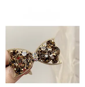 Close-up of champagne crystal bow hair clip with gold metal frame and rhinestones