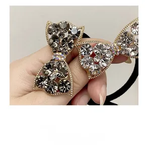 Detailed close-up of rhinestone bow hair tie with sparkling grey and clear crystals
