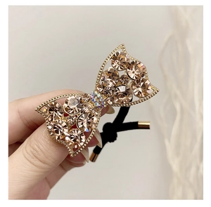 Close-up of sparkling rhinestone bow hair tie with champagne crystals and golden metal frame