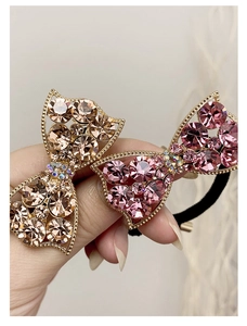 Detail view of sparkling rhinestone bow hair ties in champagne and pink metallic finishes