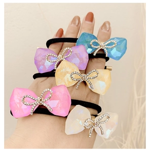 Close-up of colorful resin bow hair ties with rhinestone center worn on hand