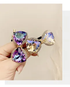 Close-up of bow-shaped hair tie with purple and iridescent crystals and gold rhinestone trim