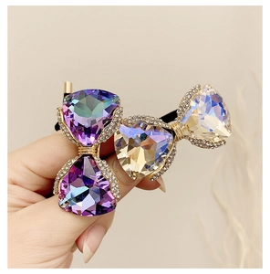 Detail of luxury hair tie featuring large triangular crystals in purple and champagne