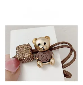 Detail of high-elasticity hair tie featuring a golden bear charm and a rhinestone cube