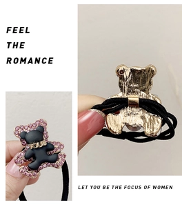 Close-up of black matte bear hair tie with pink crystals and gold metal logo detail