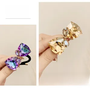 Detail of bow-shaped crystal hair ties with purple and amber faceted gems on black band
