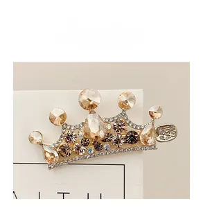 Dettaglio del fermaglio per capelli a corona con strass champagne e ciondolo inciso
