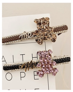 Close-up of rhinestone bear hair clips with me letters and woven texture detail