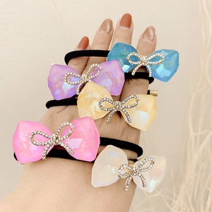 Five colorful crystal bow hair ties with rhinestone accents worn on a woman's wrist