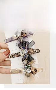 Detailed view of three rhinestone organza bow hair clips with pearls in various colors