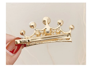 Dettaglio del retro della clip per capelli a corona dorata con chiusura a becco d'anatra