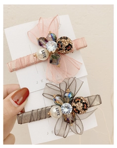 Detail of pink and grey organza bow hair clips with rhinestones, pearls and leopard balls