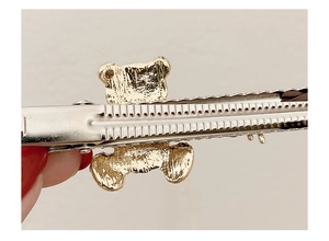 Detail of silver alloy duckbill hair clip showing non-slip teeth and gold bear ornament