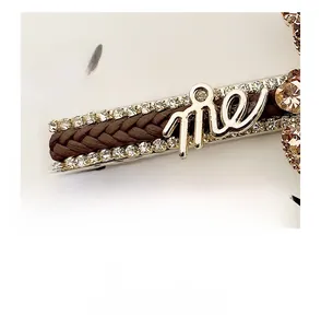 Macro view of gold alloy hair clip with rhinestones, brown woven leather and me detail