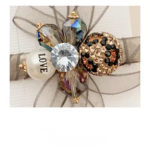Detail view of floral organza duckbill clip with rhinestones and LOVE pearl bead