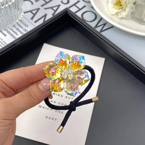Détail d'un élastique à cheveux fleur de lotus en cristal avec bande noire et embouts dorés