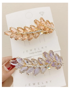 Detail showing leaf-shaped pink crystal hair clips with sparkling rhinestone inlay and alloy base