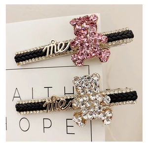 Close-up of sparkling rhinestone bear and me logo on black woven hair clips