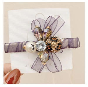 Close-up of purple organza bow hair clip with rhinestones and pearl detail