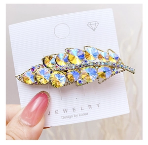 Close-up of leaf-shaped hair clip featuring colorful crystals and golden alloy base