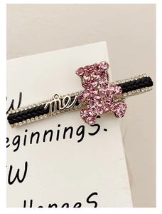 Detailed close-up of a pink crystal bear hair clip with me letter and white rhinestones