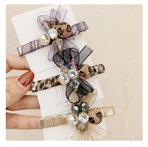 Close-up of three organza bow hair clips with rhinestones, pearls and leopard print