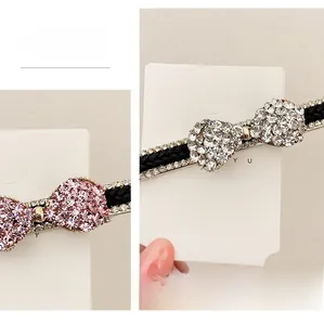 Détail de barrettes à nœuds en strass roses et blancs avec ruban noir tressé