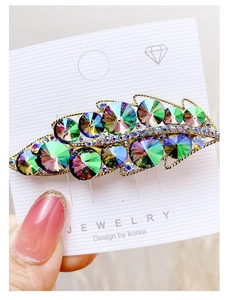Macro shot of colorful rhinestone leaf hair clip with gold alloy base on display card