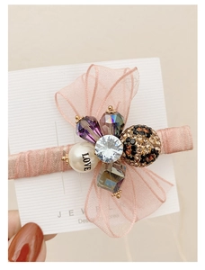Detailed close-up of pink organza bow hair clip with luxury rhinestone and pearl accents