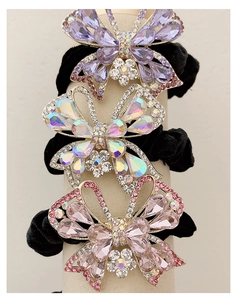 Dettaglio di elastici per capelli in velluto con strass brillanti viola e rosa