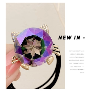 Detailed macro view of a cat-shaped hair tie featuring a gradient purple crystal stone