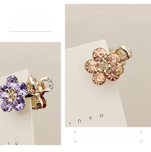 Detail view of mini flower hair clips with purple and champagne crystal rhinestones