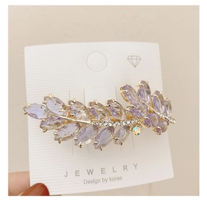 Detailed macro view of purple marquise crystal leaf hairpin with gold metal base