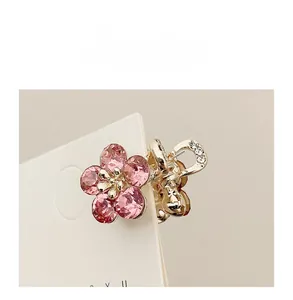 Detail shot of mini gold flower hair claw clip with pink crystals and small white rhinestones