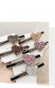 Detailed macro view of woven rope hair clips with rhinestone hearts and Loveme text