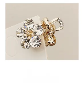 Close-up detail of small golden floral hair claw with sparkling crystal rhinestones