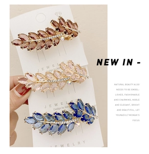 Detailed close-up of three crystal leaf spring hair clips in amber, pink, and blue shades