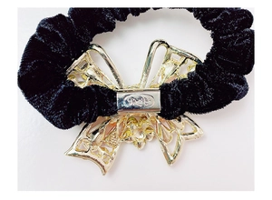 Dettaglio del retro dell'ornamento a farfalla dorata su un elastico in velluto nero