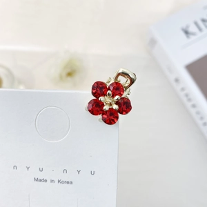 Macro shot of small red crystal flower hair claw clip on white display card