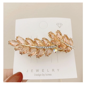 Macro detail of champagne crystal leaf hair clip with rhinestones on gold alloy base
