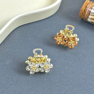 Close-up of small metal hair claws with crystal flower designs in gold finish