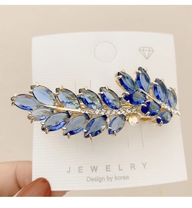 Close-up of blue crystal leaf hair clip with marquise-cut stones and gold metal base