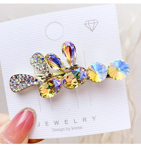 Detailed macro view of gold duckbill hair clip with purple rhinestones and drop crystals