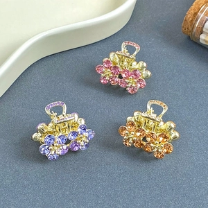 Close-up of three mini flower hair claws with colorful rhinestones on gold metal base